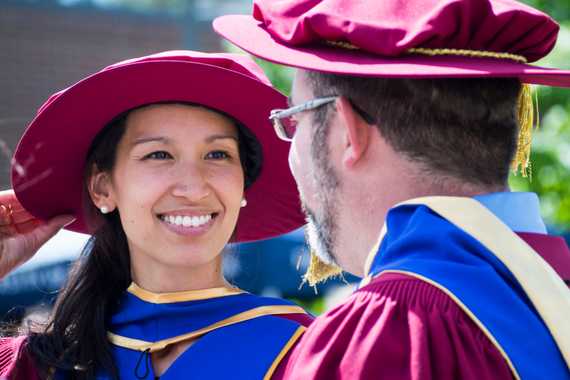 A smiling UBC doctoral graduates dressed in regalia